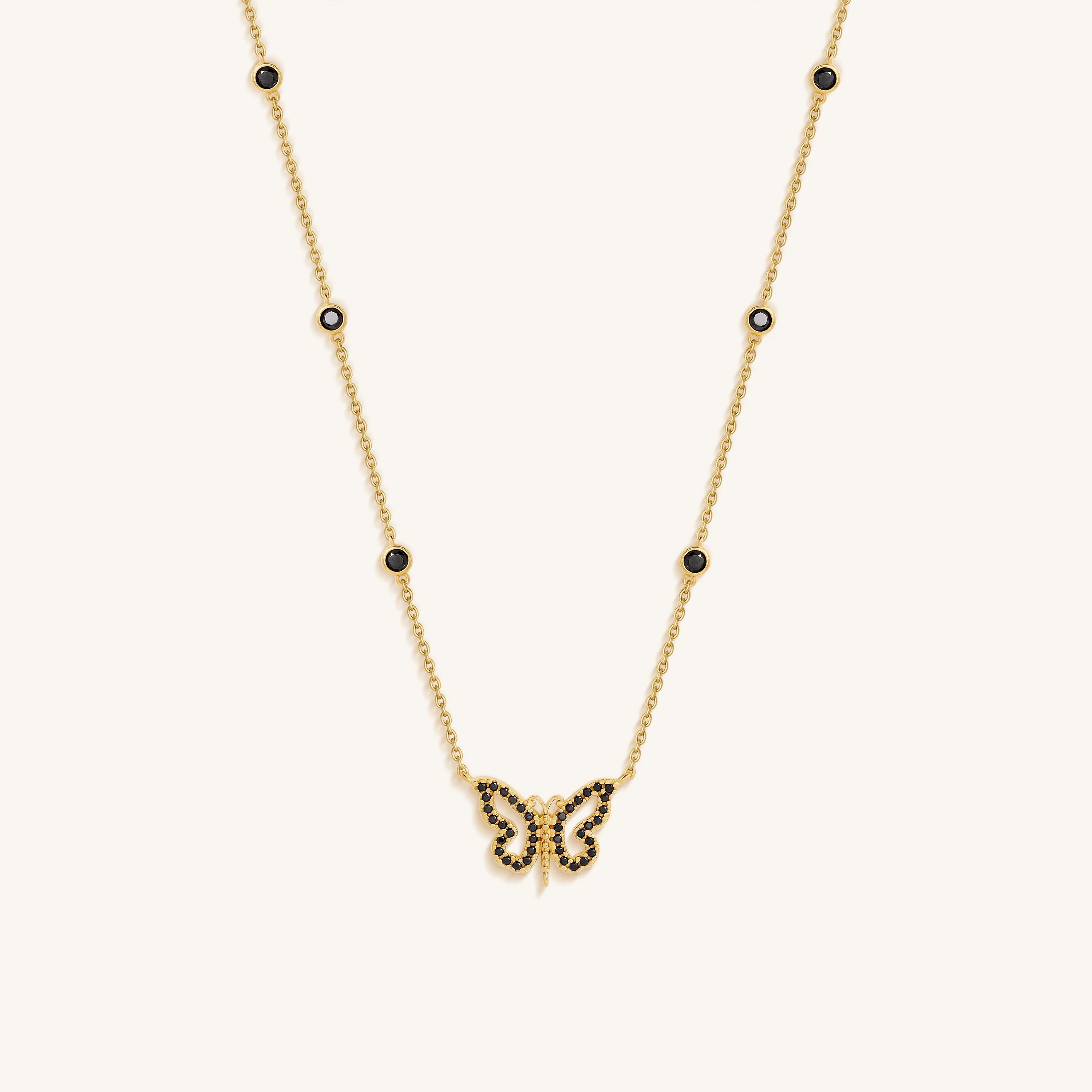 Gold butterfly necklace with black stones on a white background