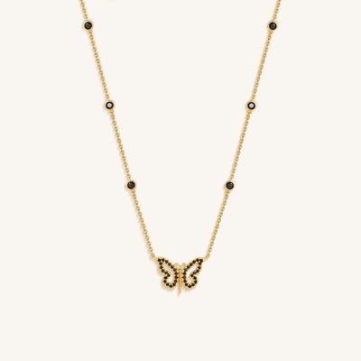 Gold butterfly necklace with black stones on a white background